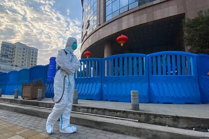 ARCHIVO - En esta fotografía de archivo del 6 de febrero de 2021, un trabajador con equipo de protección camina afuera del Hospital Central de Wuhan, en China, donde el médico Li Wenliang hizo sonar las armas en los primeros días de la pandemia de coronavirus. (AP Foto/Ng Han Guan, Archivo)