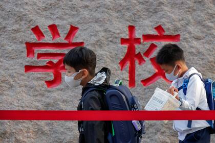 ARCHIVO - En esta fotografía del 7 de septiembre de 2020, alumnos con mascarillas para protegerse del coronavirus llegan a su escuela primaria, en Beijing. (AP Foto/Andy Wong, archivo)
