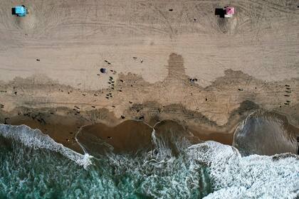 ARCHIVO - En una fotografía aérea tomada con un dron, cuadrillas de trabajadores realizan tareas de limpieza tras el derrame de crudo en Huntington Beach, California, el 11 de octubre de 2021. (AP Foto/Ringo H.W. Chiu, archivo)