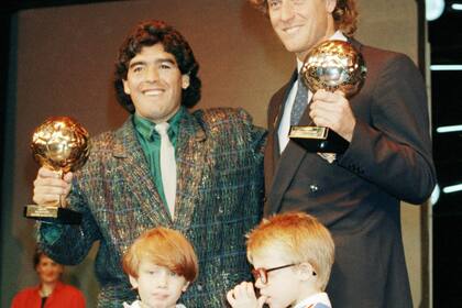 ARCHIVO - Foto del 13 de noviembre de 1986, la estrella argentina Diego Maradona posa con el portero alemán Harald Schumacher con sus premios tras la Copa Mundial 1986. El martes 7 de mayo del 2024, reaparece el Balón de Oro perdido que ganó Maradona en 1986 y será subastado en París. (AP Foto/Michael Lipchitz, Archivo)