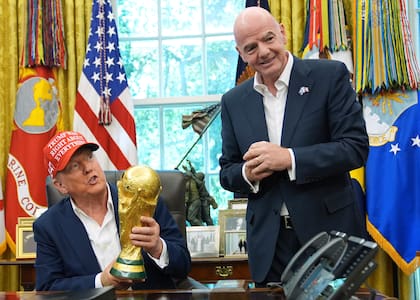 ARCHIVO - Foto del 22 de agosto del 2025, el presidente Donald Trump sostiene el trofeo al campeón de la Copa Mundial en una reunión en la Oficina Oval con el presidente de la FIFA Gianni Infantino. (AP Foto/Jacquelyn Martin, Archivo)
