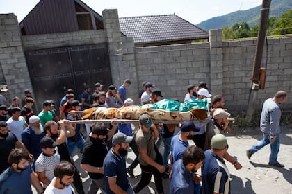 ARCHIVO - Gente cargando el cuerpo de una víctima de asesinato identificada como Zelimkhan Khangoshvili, un georgiano musulmán, en su funeral en el poblado de Duisi, en el valle de la Garganta del Pankisi, en Georgia, el 29 de agosto de 2019.  (AP Foto/Zurab Tsertsvadze, archivo)