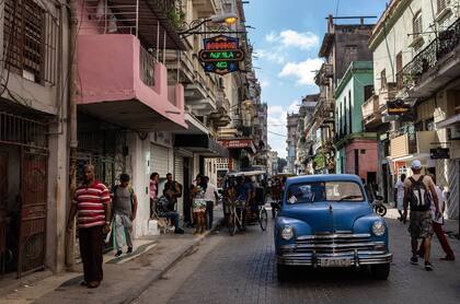 Archivo.- La gente camina bajo un cartel que anuncia una tienda de comestibles privada, a la izquierda, en La Habana, Cuba, el 11 de noviembre de 2023