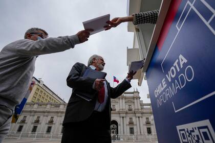 ARCHIVO - La gente recibe una copia del borrador de una nueva Constitución afuera del palacio presidencial de La Moneda en Santiago, Chile, el 17 de noviembre de 2023. Los chilenos tienen hasta el 17 de diciembre para estudiar los artículos y decidir si reemplazará la Constitución actual, impuesta por la dictadura militar hace 41 años. (AP Foto/Esteban Félix, Archivo)
