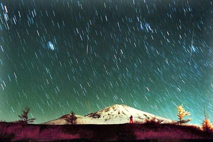 ARCHIVO - La lluvia de meteoritos Leónidas es vista en el cielo sobre el nevado Monte Fuji, la montaña más elevada de Japón, en esta imagen de 7 minutos tomada el 19 de noviembre de 2001. (AP Foto/Itsuo Inouye, archivo)