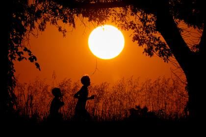 ARCHIVO - La silueta de dos personas, recortadas contra el cielo al atardecer en Shawnee Mission Park, el 26 de septiembre de 2024, en Shawnee, Kansas. (AP Foto/Charlie Riedel, archivo)
