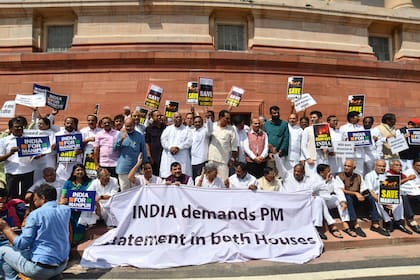 ARCHIVO - Legisladores de oposición que exigen una declaración del primer ministro Narendra Modi sobre la violencia en el estado Manipur sotienen carteles y una manta con el acrónimo "INDIA" _siglas de una alianza opositora_ frente al edificio del Parlamento, el lunes 24 de julio de 2023, en Nueva Delhi, India. (AP Foto, archivo)