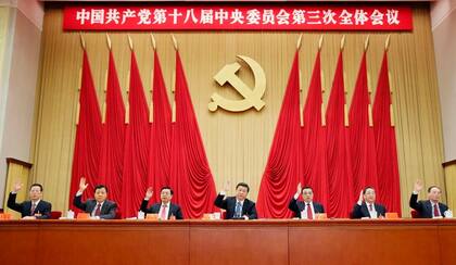 (Archivo) Los líderes del Partido Comunista Chino, con el presidente Xi Jinping en el centro, alzan la mano en una sesión plenaria en 2013