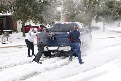 Archivo.- Los residentes ayudan a un conductor a salir del hielo en la carretera en Round Rock, Texas, el 17 de febrero de 2021, después del paso de una tormenta de invierno