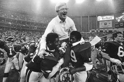 ARCHIVO - Lou Holtz, entonces entrenador de Arkansas, es levantado en hombros por Earl Buckingham (7