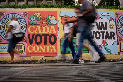 ARCHIVO - Personas caminan frente a un mural con el mensaje "Cada voto cuenta", en Sao Paulo, Brasil, el 25 de octubre de 2022. (AP Foto/Matias Delacroix, Archivo)