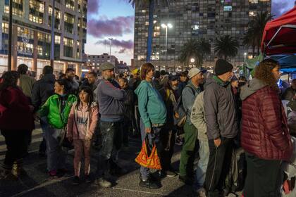 ARCHIVO - Personas hacen fila para recibir comida gratis en el centro de Montevideo, Uruguay, el 11 de octubre de 2022. (AP Foto/Matilde Campodonico, Archivo)