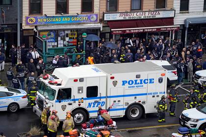 Archivo - Policías y bomberos en la entrada de una estación del metro en Brooklyn, Nueva York, tras un tiroteo en un tren el 12 de abril de 2022. (AP Foto/John Minchillo, Archivo)