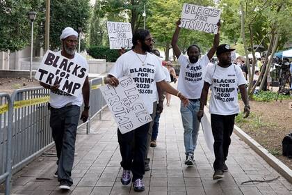 ARCHIVO - Simpatizantes del expresidente Donald Trump con carteles y camisetas en las que se lee «Negros por Trump» se reúnen cerca de la Corte Federal de Estados Unidos E. Barrett Prettyman, el 3 de agosto de 2023, en Washington. (AP Foto/Mariam Zuhaib, Archivo)