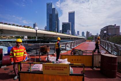 ARCHIVO - Trabajadores en un puente peatonal de Shanghái, el 9 de octubre de 2024. (AP Foto/Andy Wong, Archivo)