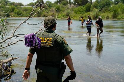 ARCHIVO - Un agente de la Patrulla Fronteriza de Estados Unidos observa a un grupo de migrantes cruzar el río Bravo para entregarse a las autoridades el 15 de junio de 2021, en Del Rio, Texas. (AP Foto/Eric Gay, archivo)