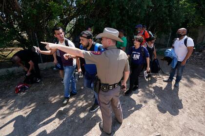 ARCHIVO - Un agente del Departamento de Seguridad Pública en Del Rio, Texas, dirige hacia un lugar a un grupo de migrantes que cruzaron la frontera y se entregaron a las autoridades. (AP Foto/Eric Gay, Archivo)