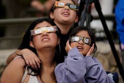 ARCHIVO - Un grupo de espectadores utiliza unas gafas especiales para ver cómo la Luna se desplaza por delante del Sol durante un eclipse solar anular, o anillo de fuego, el sábado 14 de octubre de 2023, visto desde San Antonio. (AP Foto/Eric Gay, Archivo)