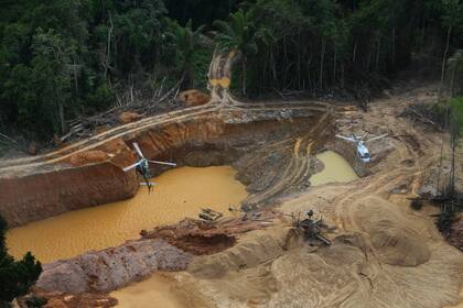 ARCHIVO - Un helicóptero de la Agencia Ambiental de Brasil sobrevuela un campamento de minería ilegal en una operación para tratar de contener esa actividad en el territorio indígena yanomami, en el estado Roraima, Brasil, el 11 de febrero de 2023. (AP Foto/Edmar Barros, Archivo)
