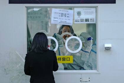 ARCHIVO - Un hombre abre la boca para una prueba de COVID-19 en un centro de pruebas en Beijing, el martes 6 de diciembre de 2022. En un brusco cambio de rumbo, China anunció el miércoles varias medidas para retirar algunas de las restricciones más duras contra el COVID-19. (AP Foto/Andy Wong, Archivo)