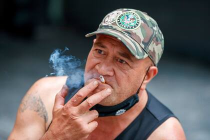 ARCHIVO - Un hombre fuma sentado en Auckland, Nueva Zelanda, el jueves 9 de diciembre de 2021. Nueva Zelanda aprobó el martes una ley con una inusual estrategia de retirar el tabaco de forma gradual con un veto permanente a que los jóvenes compren cigarrillos. (AP Foto/David Rowland, Archivo)