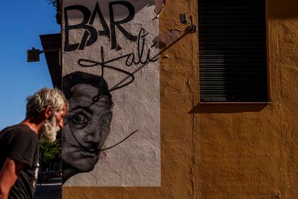ARCHIVO - Un hombre pasa junto a un dibujo que representa al artista surrealista español Salvador Dalí durante un día caluroso y soleado en Madrid, España, el jueves 13 de julio de 2023. (Foto AP/Manu Fernandez, archivo)