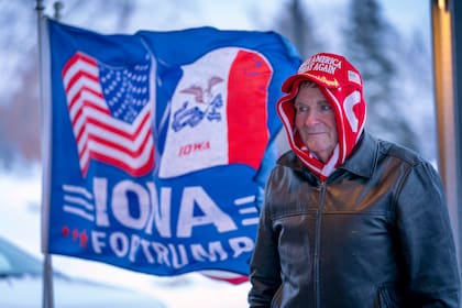 ARCHIVO - Un hombre se detiene al frente de una bandera de la campaña a favor del expresidente Donald Trump, afuera de un restaurante de la cadena Machine Shed en Urbandale, Iowa, el 11 de enero de 2024. (AP Foto/Andrew Harnik, archivo)