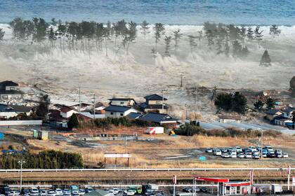 ARCHIVO - Un tsunami golpea las costas de Natori, Japón, después de un poderoso terremoto el 11 de marzo de 2011. (Kyodo News vía AP, Archivo)