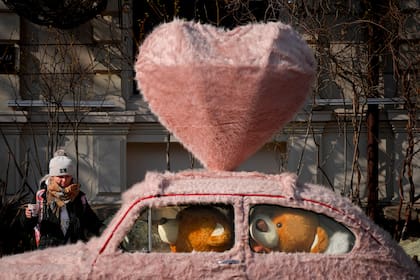 Archivo.- Una mujer camina junto a un auto decorado con pieles y ositos de peluche en Bucarest, Rumania, el martes 14 de febrero de 2023