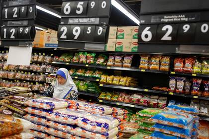 ARCHIVO - Una mujer malasia revisa bolsas de arroz en un supermercado en las afueras de Kuala Lumpur, Malasia, el 8 de agosto de 2015. (AP Foto/Joshua Paul, Archivo)