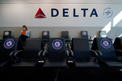 ARCHIVO - Una pasajera con mascarilla espera en un área de distanciamiento social para un vuelo de Delta Airlines, el miércoles 3 de febrero de 2021, en el Aeropuerto Internacional Hartsfield-Jackson de Atlanta. (AP Foto/Charlie Riedel, archivo)