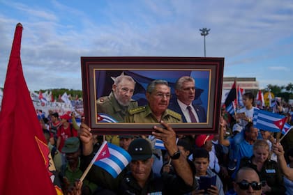 ARCHIVO - Una persona lleva en una marcha un cuadro con una imagen compuesta de Fidel Castro, Raúl Castro y del presidente de Cuba, Miguel Díaz-Canel, en la plaza de la Revolución en La Habana, el 1 de mayo de 2025. (AP Foto/Ramon Espinosa, Archivo)