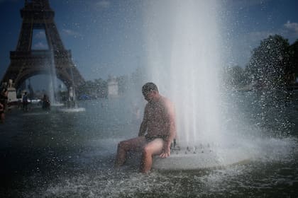 ARCHIVO - Una persona se refresca en la fuente del Trocadero, cerca de la Torre Eiffel, durante una ola de calor en París, el 24 de junio de 2026. (Foto AP/Christophe Ena, archivo)