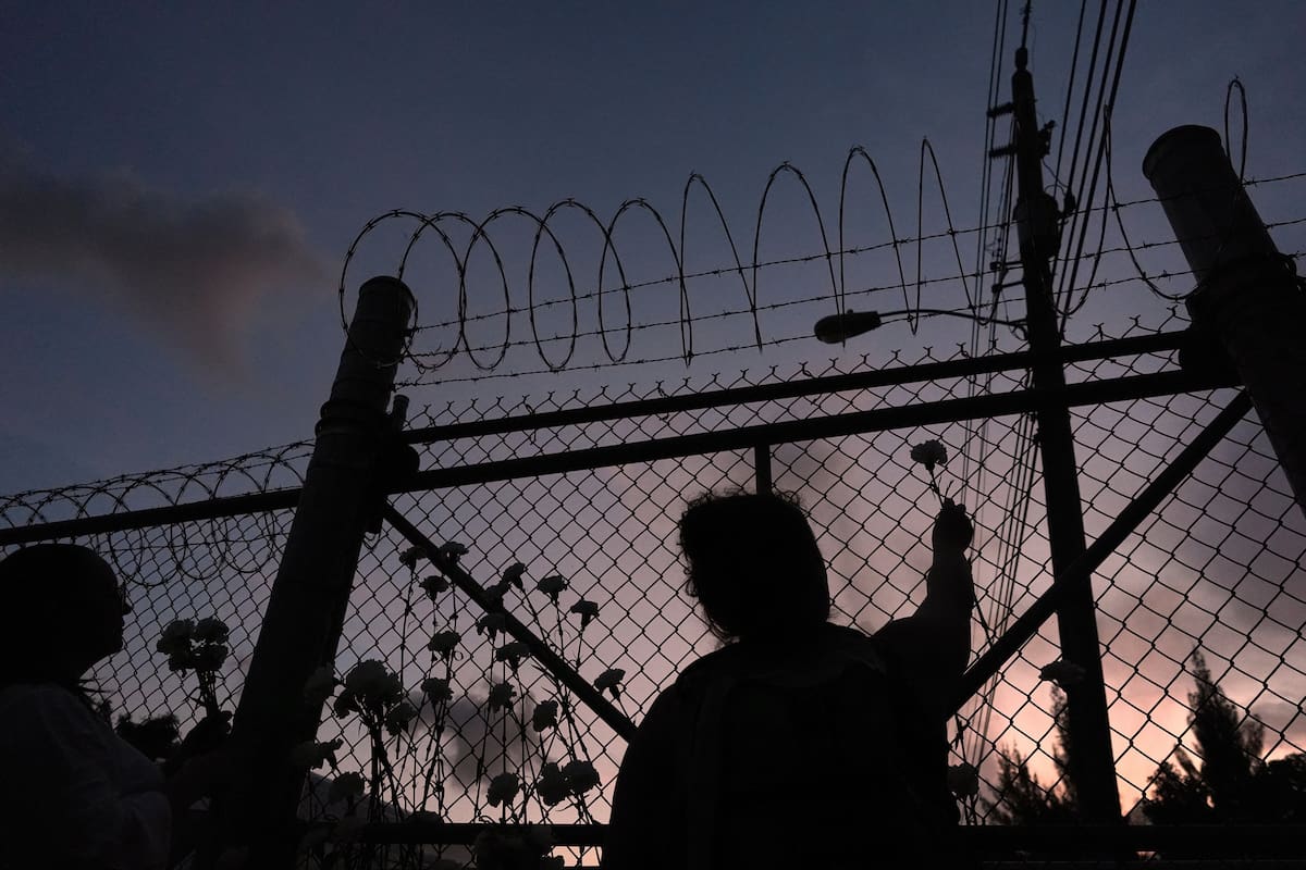 ARCHIVO – Varias personas observan las flores en una cerca fuera del Centro de Detención Krome en Miami, en 2025