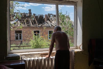 ARCHIVO - Victor Rosenberg, de 81 años, mira por la ventana rot de su vivienda destruida por un cohete ruso en el centro de Bajmut, 1 de julio de 2022. (AP Foto/Efrem Lukatsky, File)
