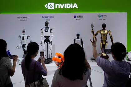 ARCHIVO - Visitantes dan órdenes a un robot en un puesto de Nvidia durante la 3ra Feria Internacional de China sobre Cadena de Suministro en el China International Exhibition Center, Beijing, el 18 de julio de 2025. (AP Foto/Mahesh Kumar A., Archivo)