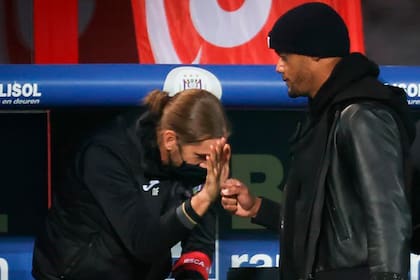 Nicolás Frutos choca las manos con Vincent Kompany en el banco durante un partido
