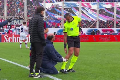 Ariel Penel es atendido por un médico mientras Héctor Paletta, cuarto árbitro, le pregunta a su compañero cómo se siente
