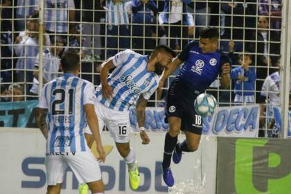 Ariel Rojas intenta cabecear, Juan Méndez procura defender y Cristian Erbes es testigo.