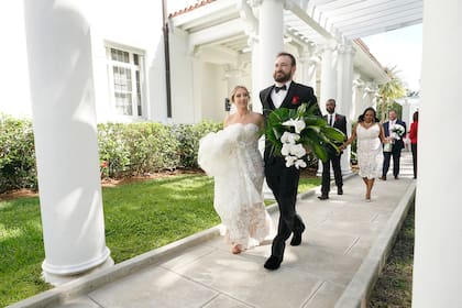 Arielle Agnelli y Bryan Arvesu se dirigen a una sesión de fotos después de casarse durante una ceremonia colectiva de bodas en el Día de San Valentín, el lunes 14 de febrero de 2022, afuera del Museo Flagler en Palm Beach, Florida. (AP Foto/Wilfredo Lee)