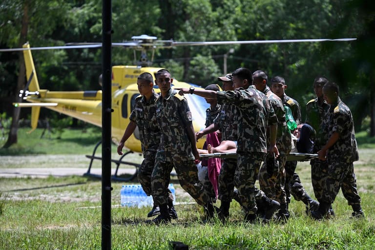 Army personnel rescue flood-affected residents using a helicopter following flash floods, as they arrive at an army camp in Battar Bazar town in Nepal's Nuwakot district on August 27, 2026. Rescue teams rushed on August 27 to find more than 1,300 people missing on the Nepal-Tibet border in flash floods and landslides that killed at least 165 and swept away entire villages. (Photo by Arun SANKAR / AFP)