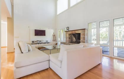 Así es su amplio living en doble altura con salida a la galería y hogar a leña.