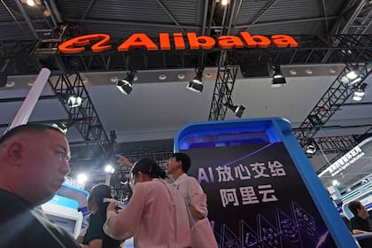 Asistentes pasan junto al puesto de Alibaba, donde un cartel dice "Descansa tranquilo dando IA a Ali Cloud" en la Conferencia Mundial de Inteligencia Artificial, en Shanghai