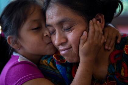 Astrid Cardona besa a su mamá Ufemia Tomás, madre de Yenifer Yulisa Cardona Tomás, durante una entrevista en Ciudad de Guatemala, el lunes 4 de julio de 2022. Yenifer Yulisa Cardona Tomás es una de las sobrevivientes de los más de 50 migrantes que fueron encontrados muertos dentro de un tractor-remolque cerca de San Antonio, Texas. (AP Foto/Oliver de Ros)