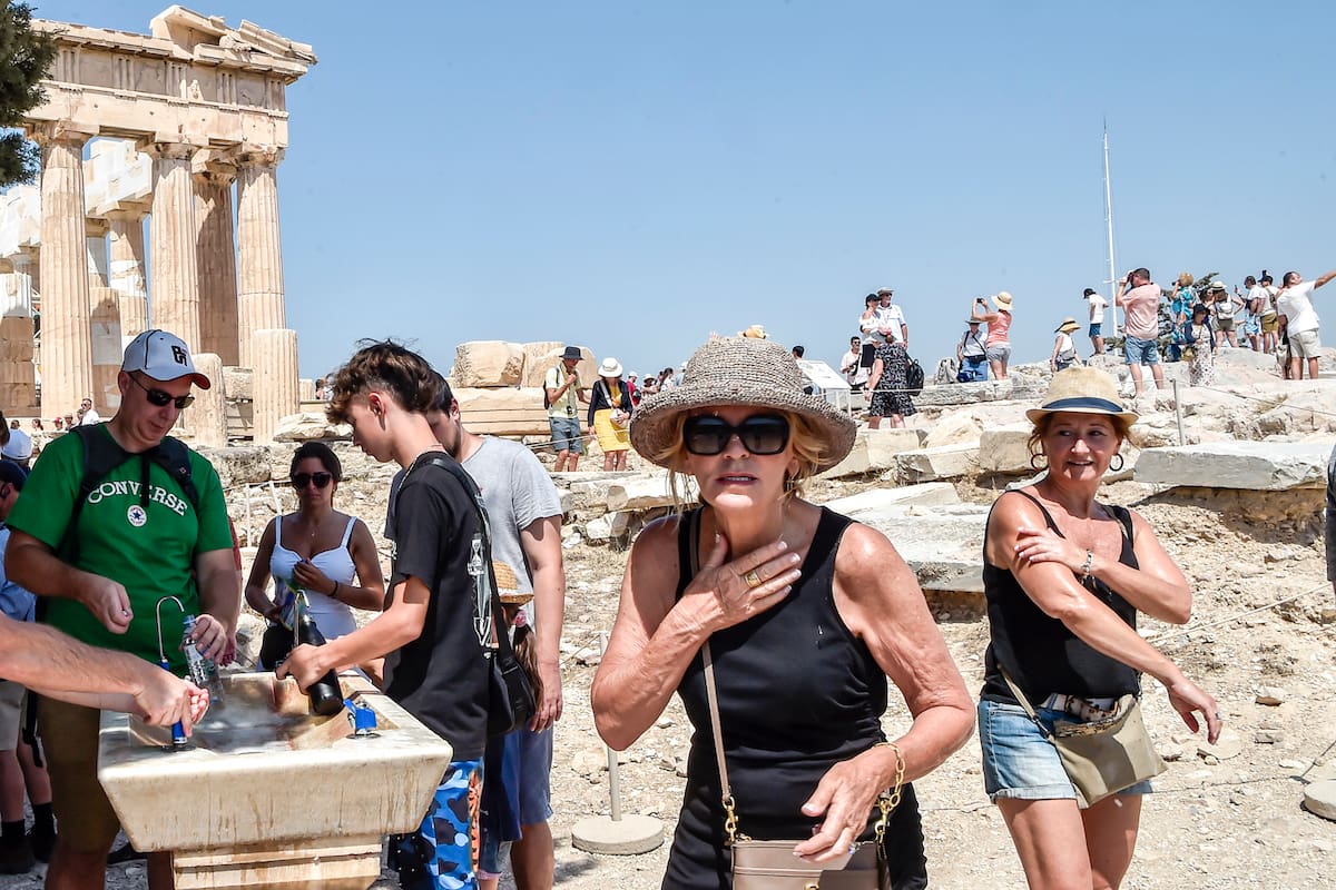 ATHENS, GREECE - JULY 20: Tourists refresh with water in front of the five century BC Parthenon temple at the Acropolis hill during a heat wave on July 20, 2023 in Athens, Greece. The Acropolis of Athens and other archaeological sites in Greece announced reduced opening hours due to the heatwave conditions. Parts of Europe continue to experience extreme conditions of the Cerberus heatwave, dubbed Charon. (Photo by Milos Bicanski/Getty Images)