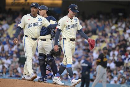 Austin Barnes, centro, de los Dodgers de Los Ángeles, observa cómo el mánager Dave Roberts (30) le da una palmadita en la espalda al lanzador abridor River Ryan, a la derecha, quien abandona un juego de béisbol por una lesión durante la quinta entrada contra los Piratas de Pittsburgh el sábado 10 de agosto de 2024, en Los Ángeles. (AP Foto/Jayne-Kamin-Oncea)