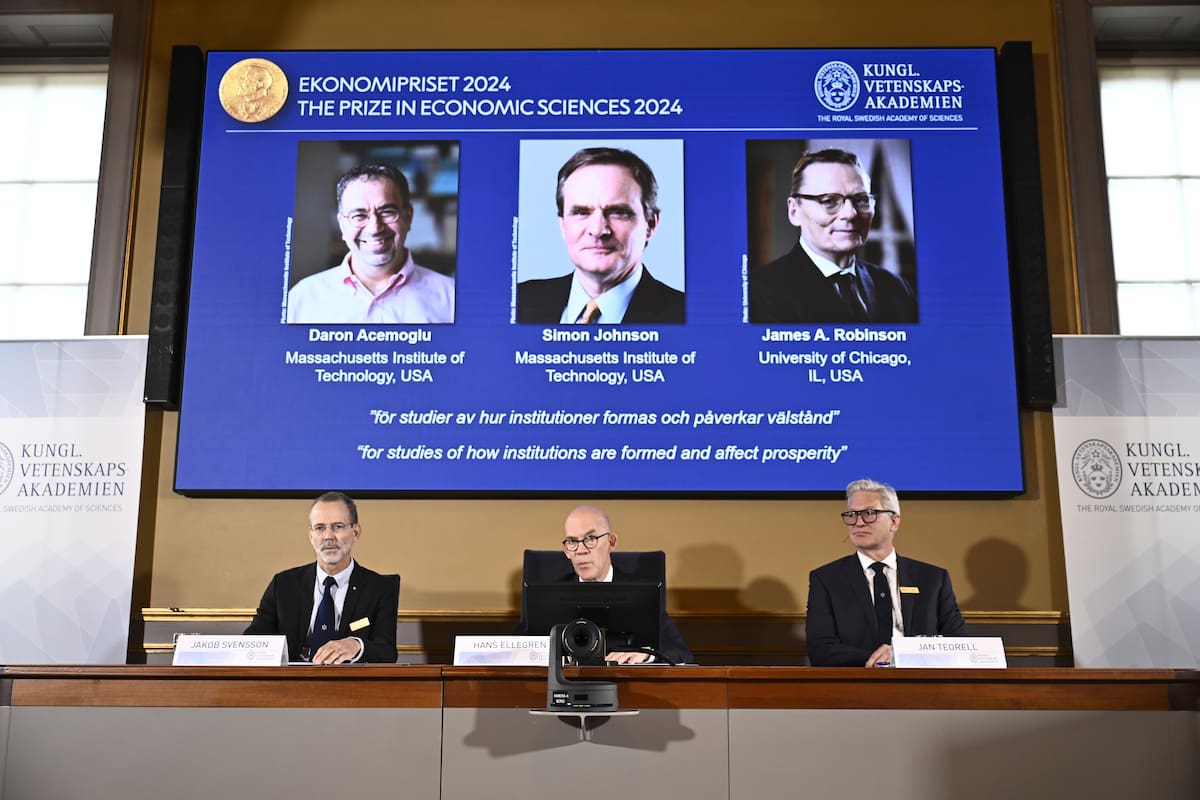 Autoridades del Nobel anuncian el Premio Nobel de Economía a Daron Acemoglu, Simon Johnson y James A Robinson, que aparecen en la pantalla detrás de ellos