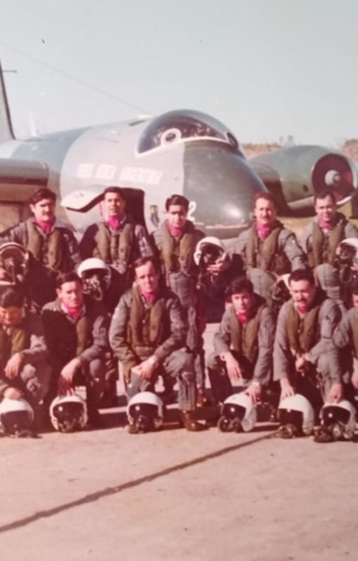 Aviadores argentinos con el pañuelo bordó en su cuello, que era distintivo del Escuadrón Canberra; en el fondo, un avión Canberra