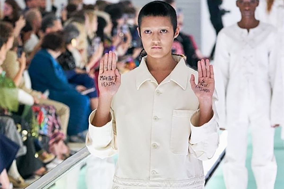 Ayesha Tan Jones levantó su mano escrita como pancarta para expresar "La salud mental no es moda" en alusión a la estética "psiquiátrica" que dominó el desfile de Alessandro Michele