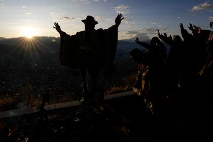 Aymaras levantan sus manos para recibir los primeros rayos de sol durante un ritual de Año Nuevo en El Alto, Bolivia, el martes 21 de junio de 2022. (AP Foto/Juan Karita)